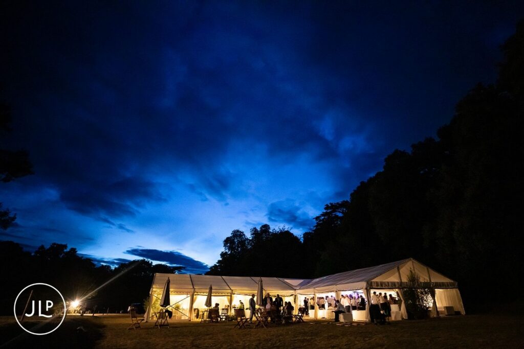 Glowing marquee at dusk for a luxury Surrey marquee wedding set against a dark blue twilight sky.