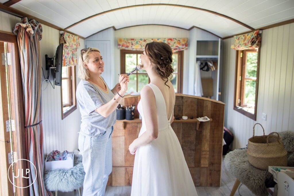 Bride having makeup applied, showcasing marquee wedding photography UK.