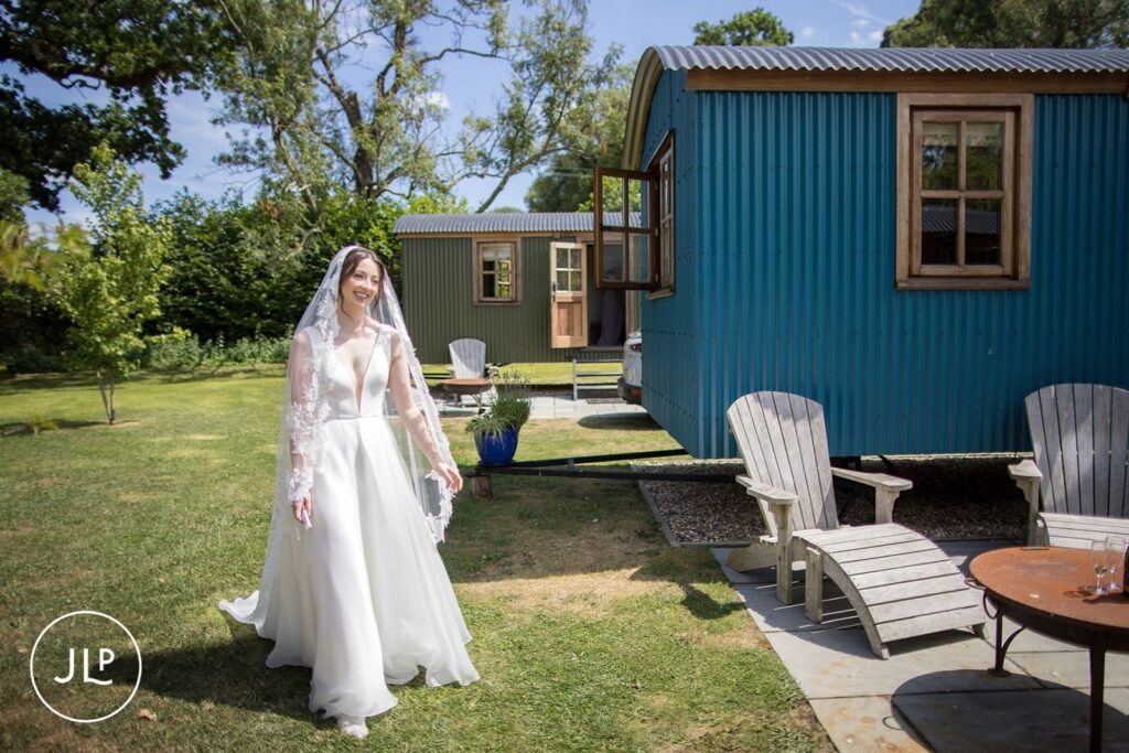 Smiling bride in Suzanne Neville gown walking at a luxury outdoor wedding Surrey.