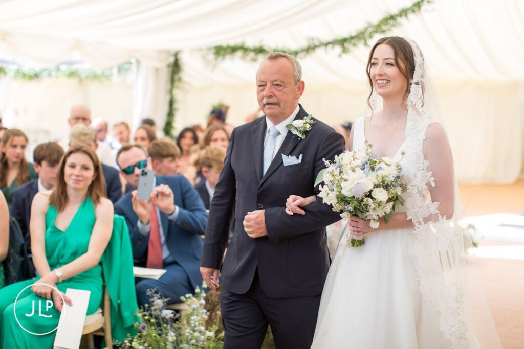 Father walking the bride down the aisle, captured by a Surrey marquee wedding photographer.