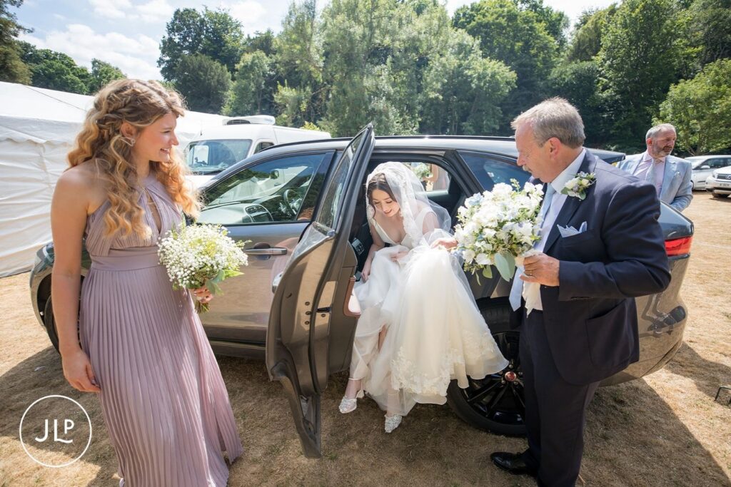 Bride arriving in a wedding car at a private estate wedding Surrey, greeted by her bridesmaids.