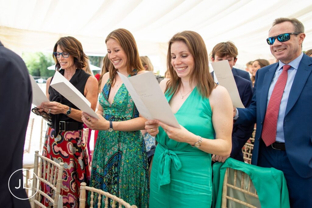 Guests laughing and singing during a heartfelt luxury Surrey marquee wedding ceremony.