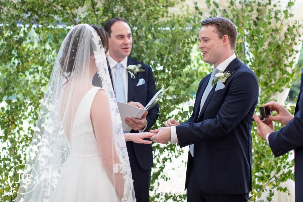 Close-up of the ring exchange during a Surrey countryside wedding ceremony.