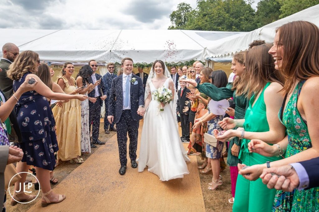 Newlyweds walking through confetti at a luxury outdoor wedding Surrey.
