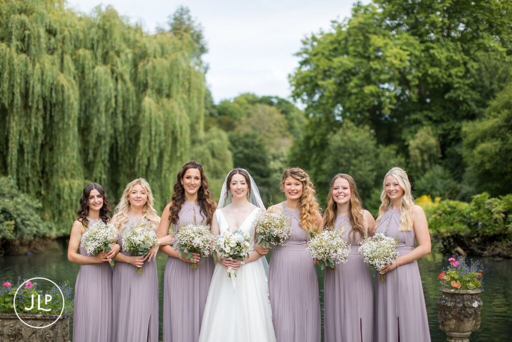 Bride and bridesmaids in lilac dresses holding baby's breath bouquets at a luxury outdoor wedding Surrey.