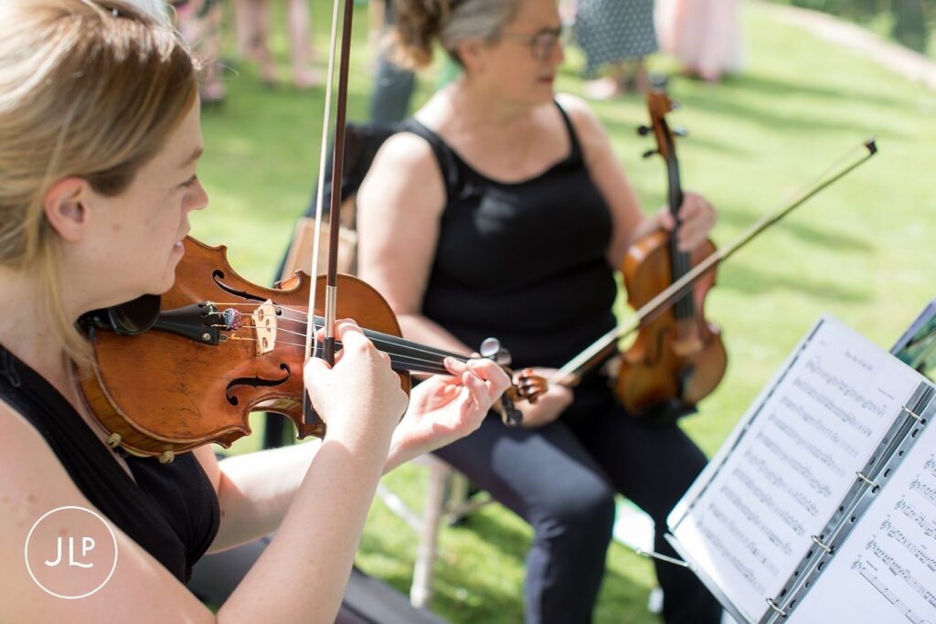 String duo performing outdoors for a romantic Surrey countryside wedding.