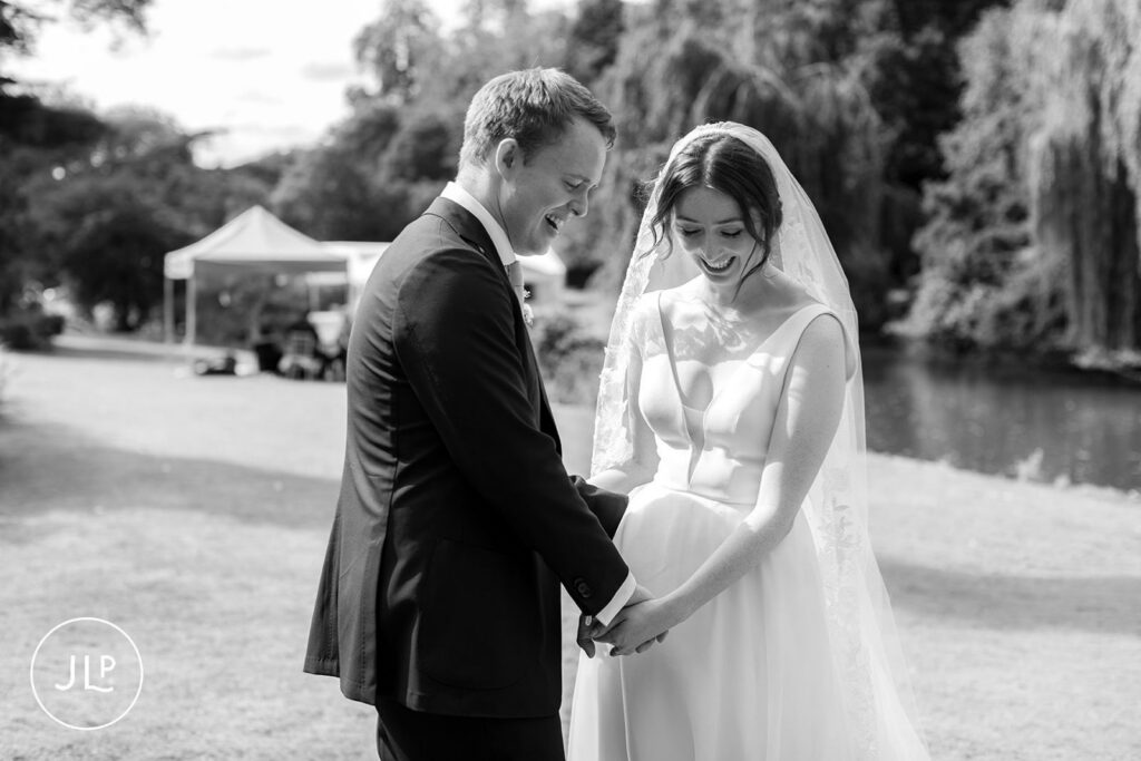 Black and white candid of a couple laughing during a luxury Surrey marquee wedding ceremony.
