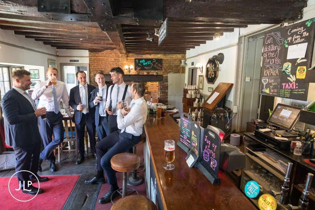 Groomsmen enjoying a pint at a local pub before a luxury outdoor wedding Surrey.