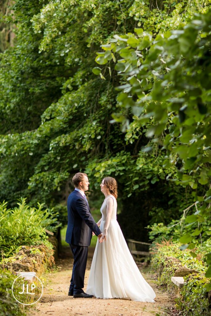 Romantic portrait of the couple framed by vibrant green foliage at a luxury Surrey marquee wedding.