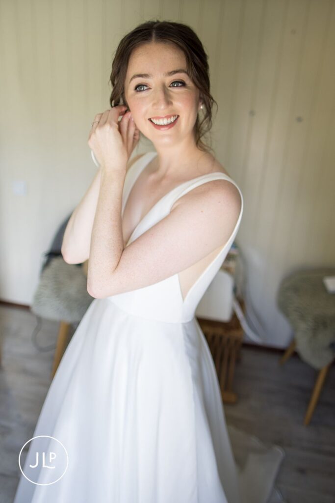 Close-up of bride putting on earrings, detailed by a Surrey countryside wedding photographer.