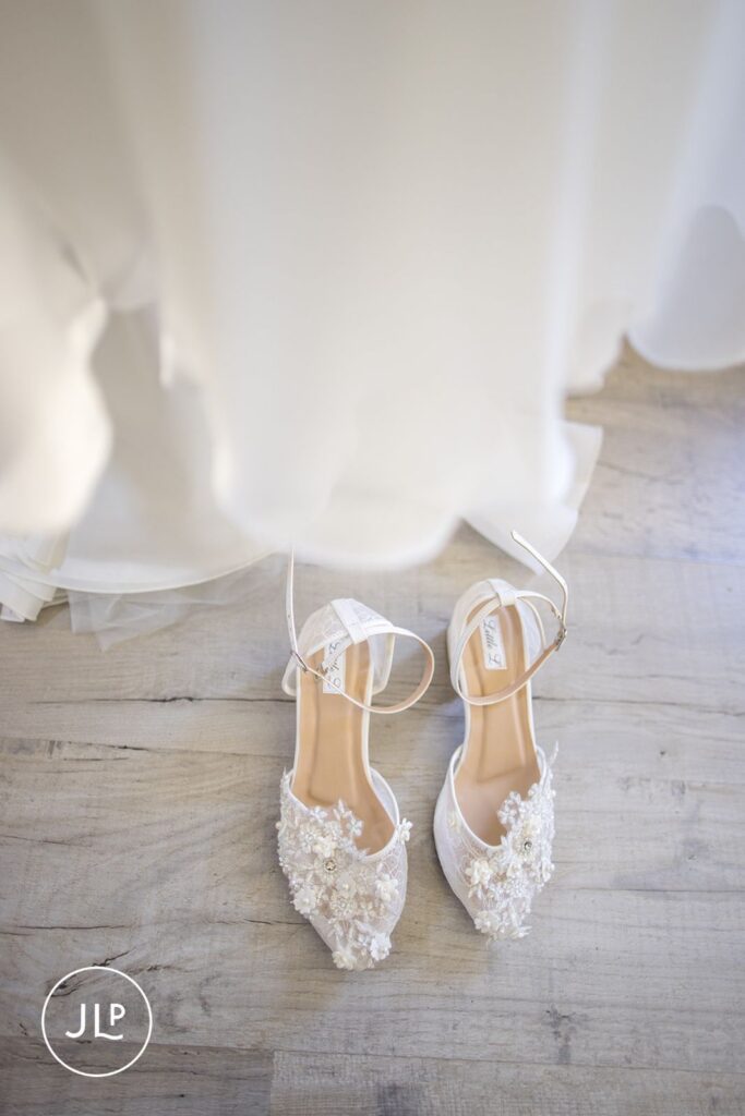 Detail shot of lace wedding shoes on wood floor from a luxury Surrey marquee wedding.
