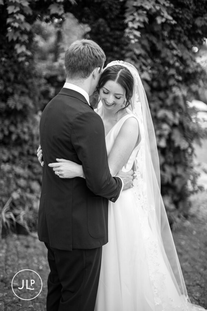 Close-up black and white candid of the couple embracing during their private estate wedding Surrey.