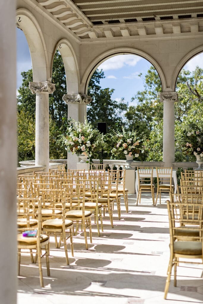 Empty gold chairs and floral arrangements set up for natural wedding photography outdoors.