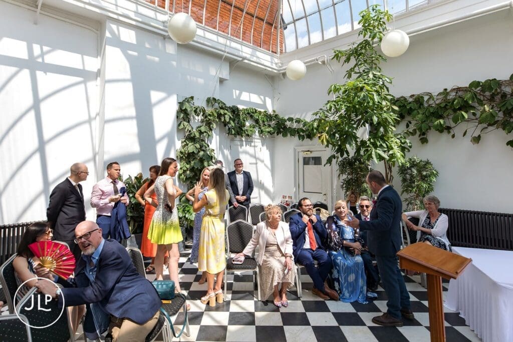 Wedding guests mingeling in the light-filled Glass House ceremony room at York House before the vows.