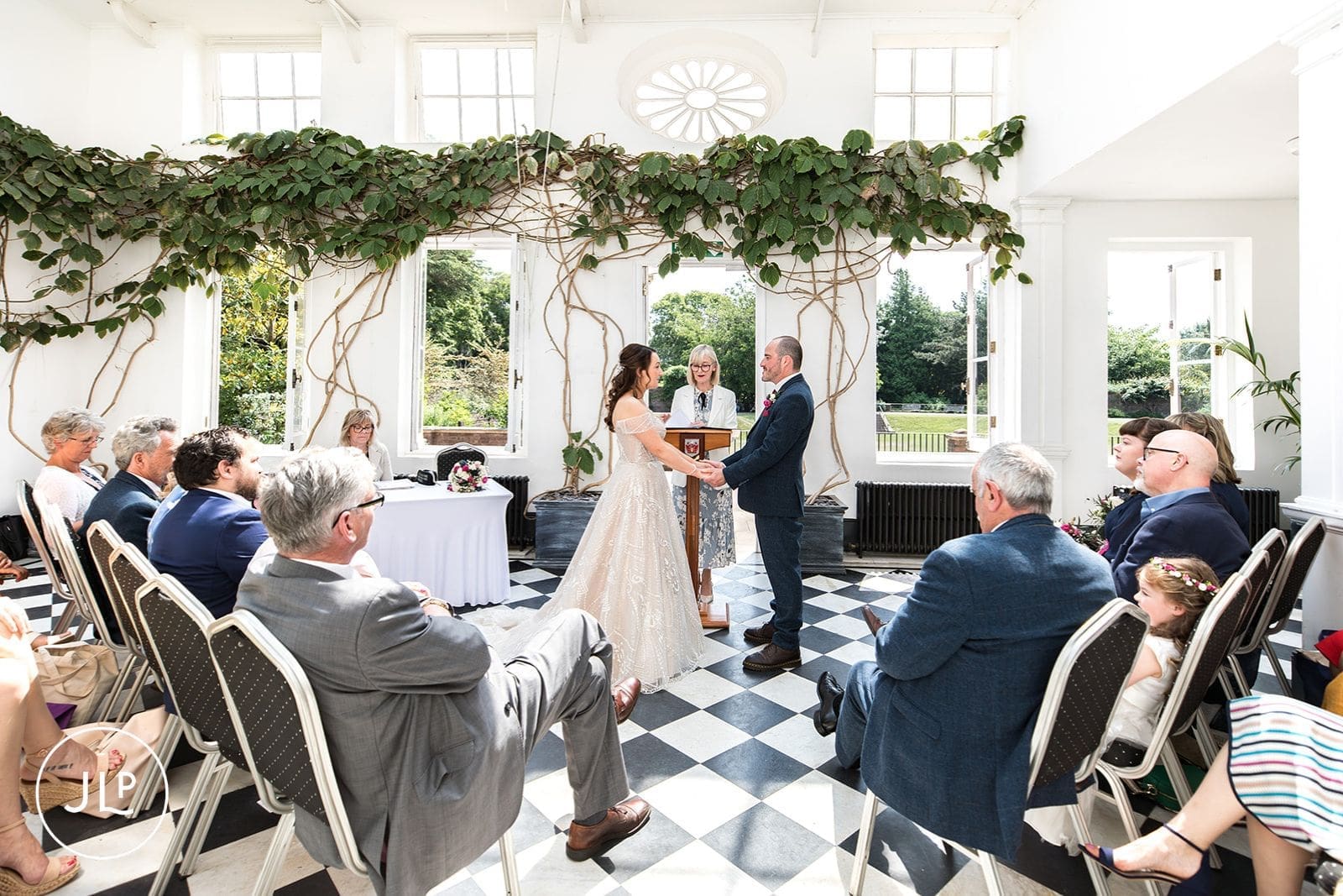 A wide view of the York House Glass House showing the bride, groom, registrar, and seated guests.