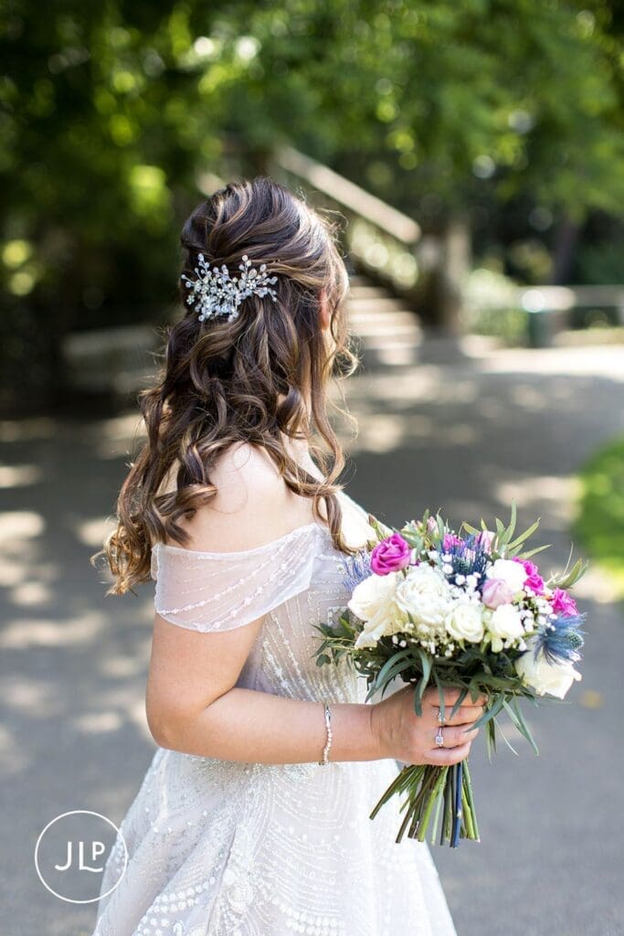 The back of a bride’s head, highlighting her wavy hair and ornate silver crystal hair clip at her summer wedding.