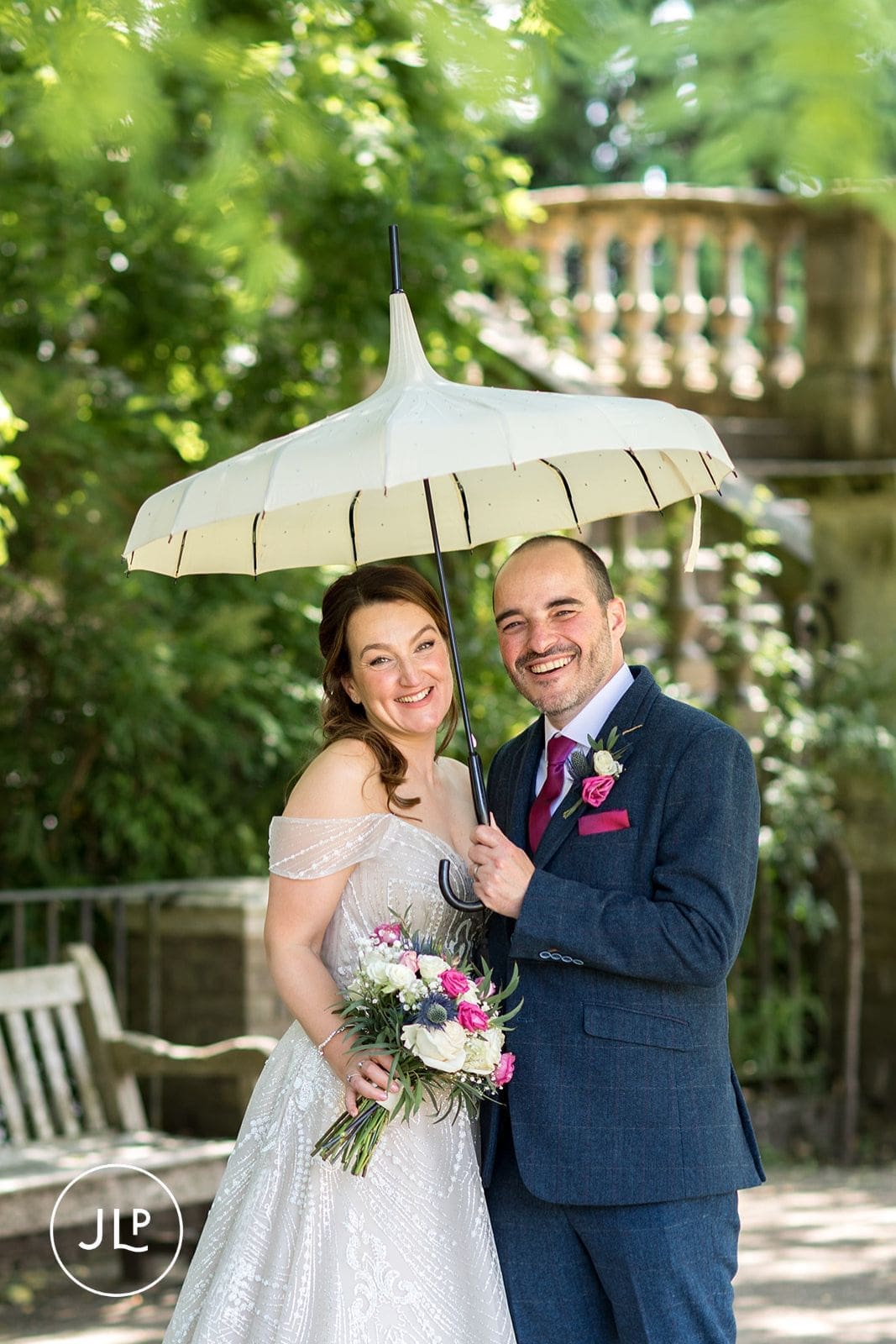 Newlyweds posing with a white umbrella during their intimate London wedding photography session.