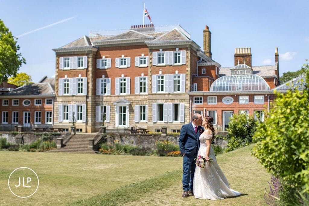 Bride and groom kissing on the lawn outside the historic venue for their York House wedding photos.