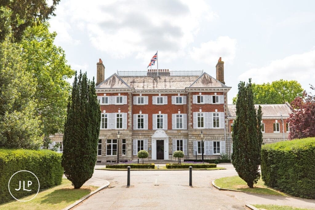 Symmetry of the historic York House building facade and manicured drive on a partly cloudy summer day.