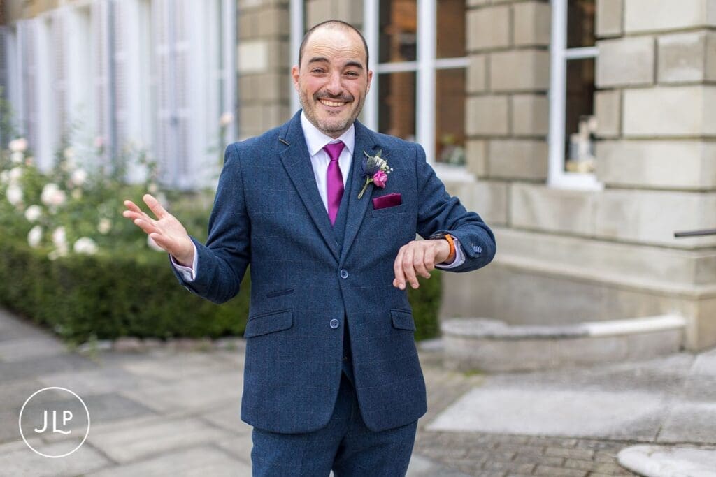 Happy groom checking his watch outside the York House registry office wedding venue in London.