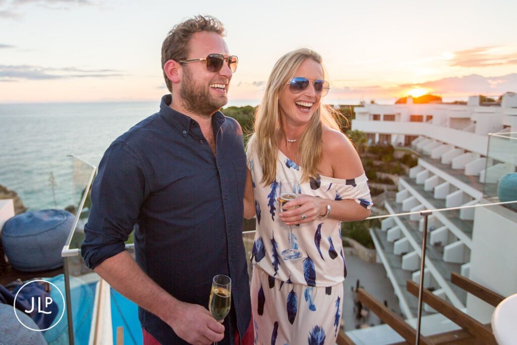 Ali and Matty laughing at their luxury Algarve wedding welcome party at sunset.