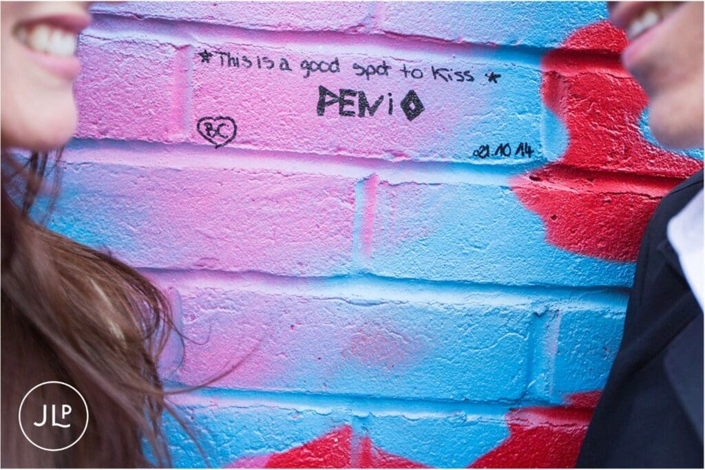 Close-up of street art text reading this is a good spot to kiss on a pre wedding shoot London.