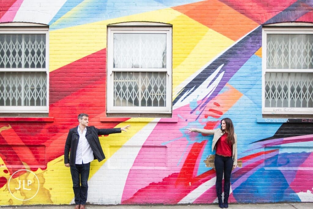 Couple posing by colorful street art during a creative Brick Lane engagement shoot.