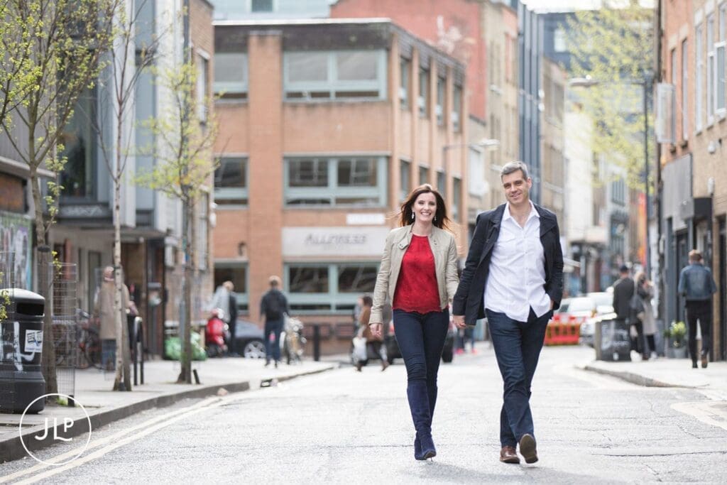 Relaxed East London engagement photography of a couple walking down a city street hand-in-hand.