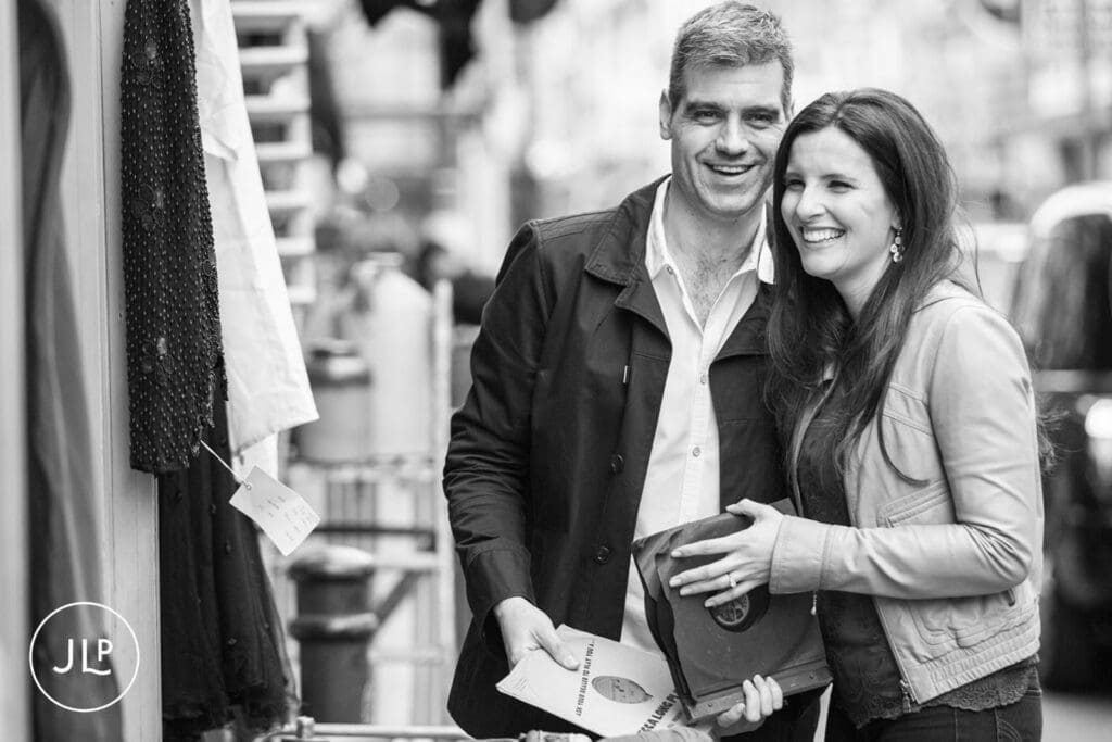 Smiling couple holding vinyl records during their relaxed Brick Lane engagement shoot.