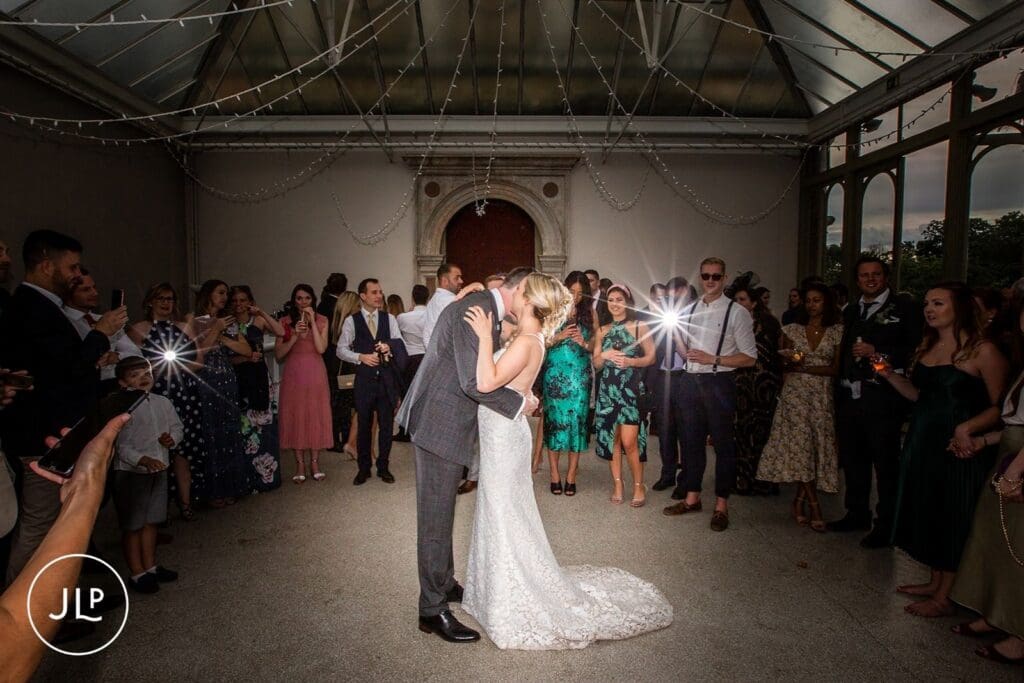 Romantic first dance during a Hampton Court House Surrey wedding reception with guests looking on.
