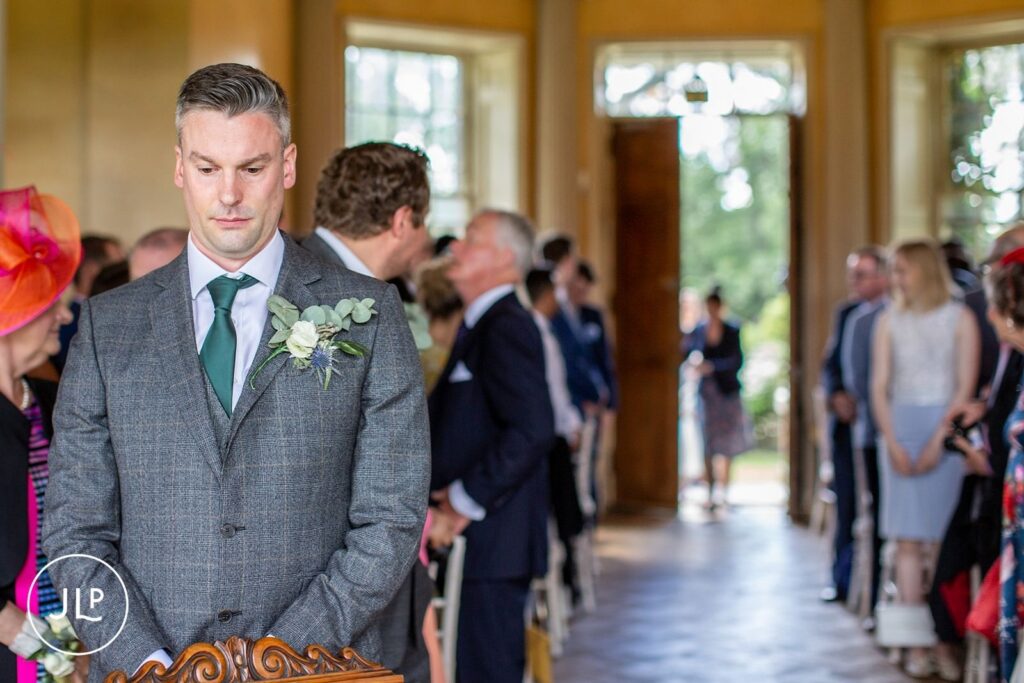 Documentary wedding photography of a groom waiting at an elegant Surrey wedding venue ceremony.