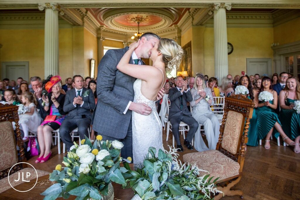 Candid wedding photography of a bride and groom's first kiss during a Hampton Court House wedding.