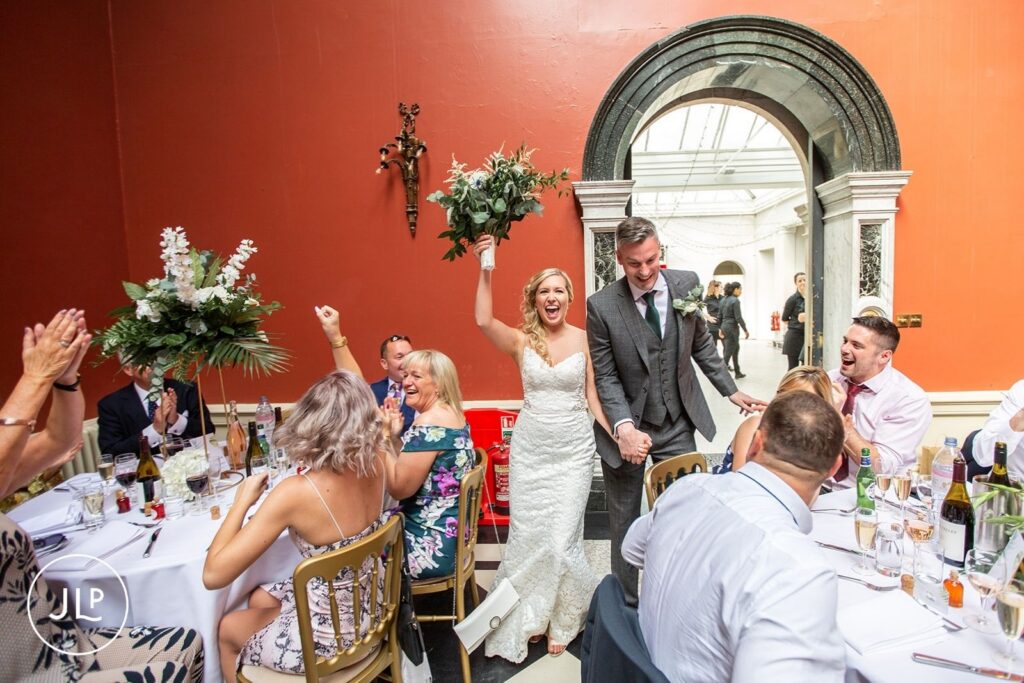 Candid wedding photography of a bride and groom entering their Hampton Court House wedding reception.