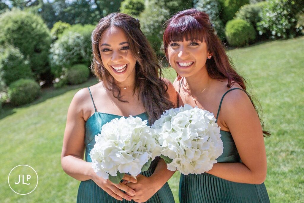 Close-up by a Hampton Court House wedding photographer featuring smiling bridesmaids with elegant white bouquets.