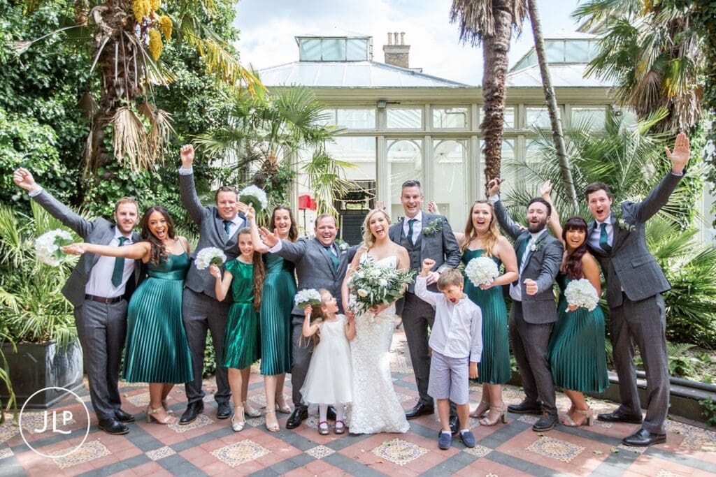 Joyful group photo by a Hampton Court House wedding photographer during an elegant Surrey wedding venue celebration.