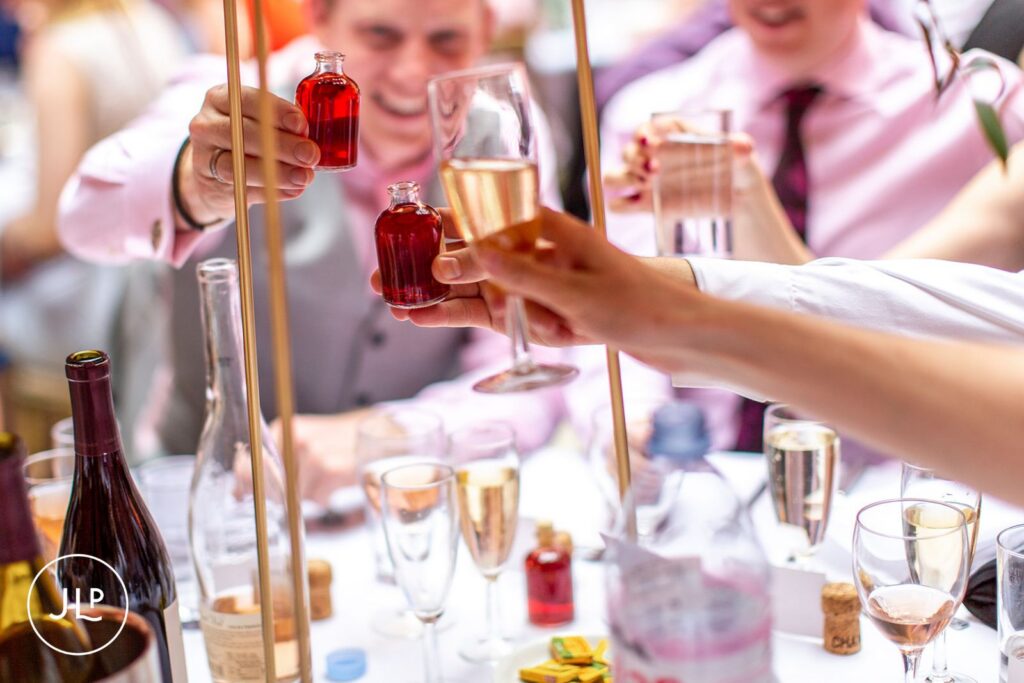 Relaxed wedding photography capturing guests toasting with favors at a Hampton Court House wedding.