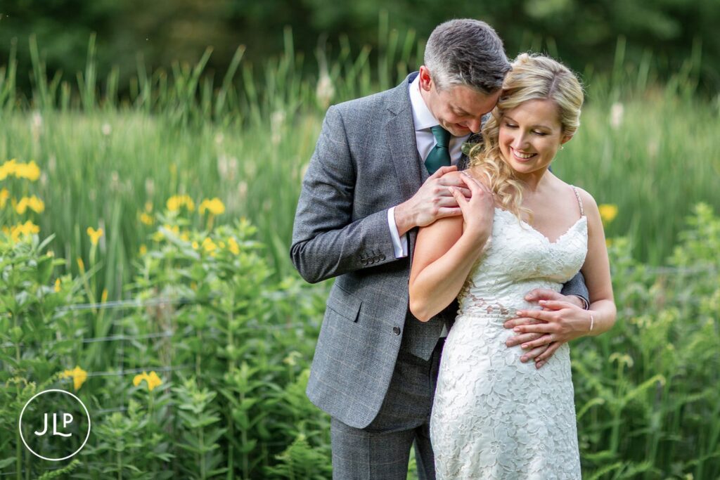 Groom embracing bride in field, a beautiful example of natural wedding photography in Surrey.