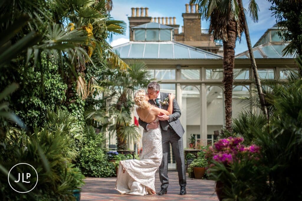 Groom dipping and kissing bride outdoors at an elegant Surrey wedding venue.