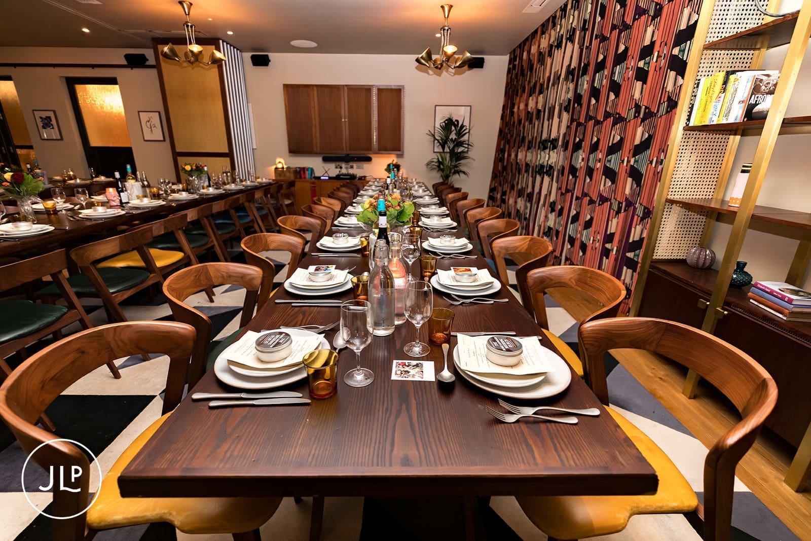 Empty long wooden dining tables meticulously set for an intimate reception dinner at The Hoxton Holborn.