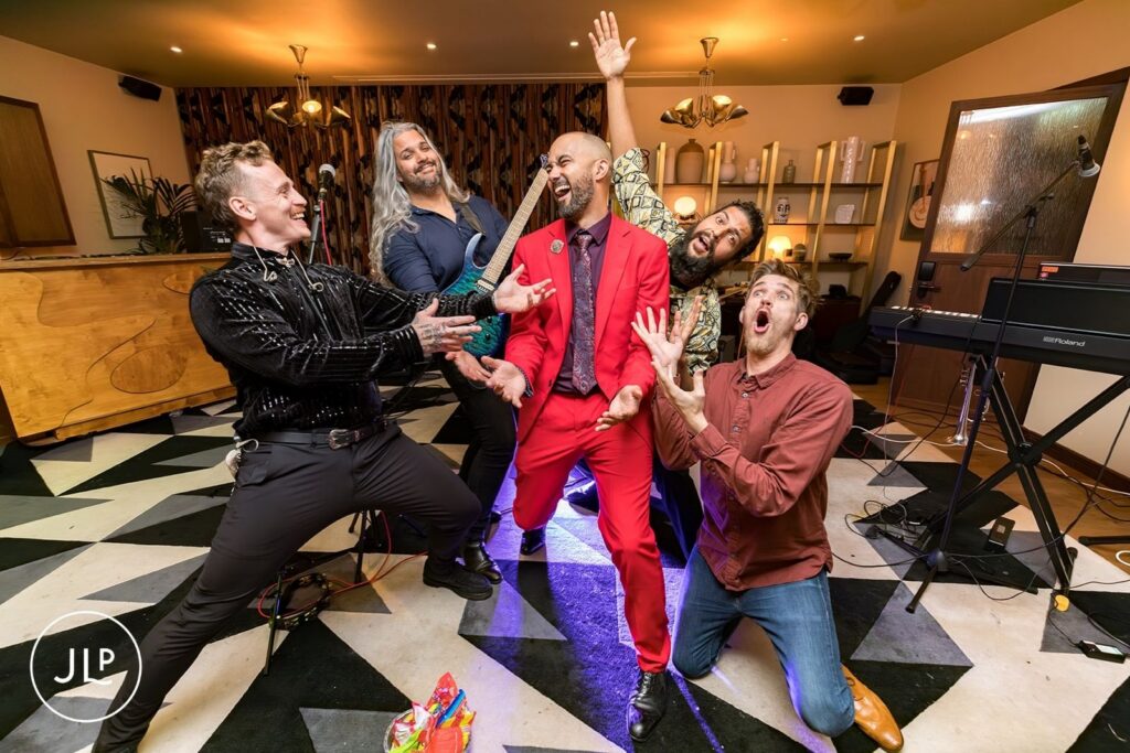Fun London wedding photographer captures a live band and groom in a red suit posing at a stylish London wedding.