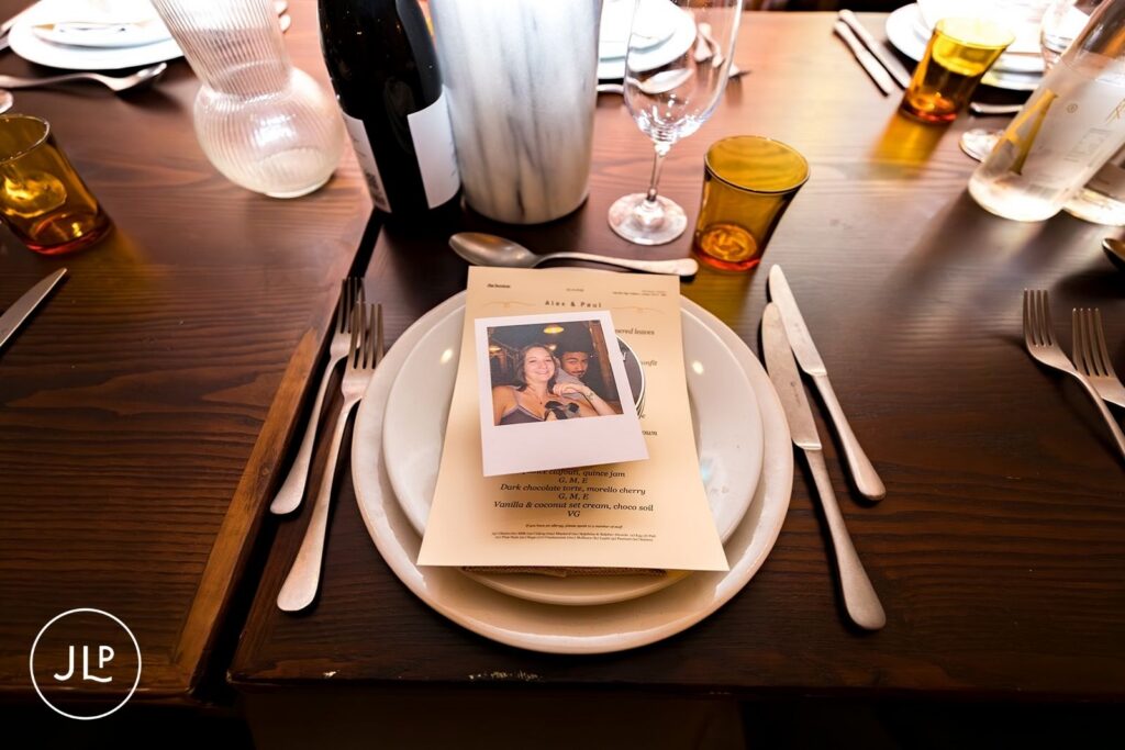 A personalized wedding menu on a white dinner plate featuring a Polaroid photo and a list of dessert courses.