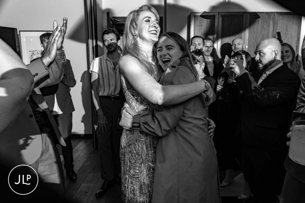 Documentary London wedding photographer candid of guests hugging and celebrating at The Hoxton Holborn.