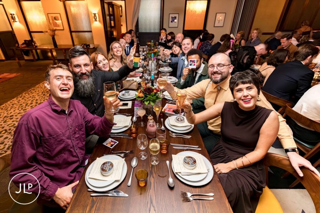 Guests at a long banquet table by a Hoxton Holborn wedding photographer for a stylish London city wedding.