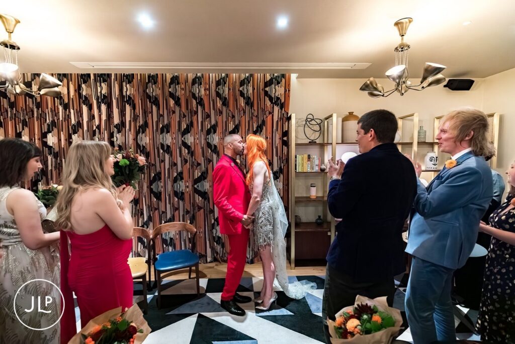 The bride and groom share a first kiss during their stylish London wedding ceremony.