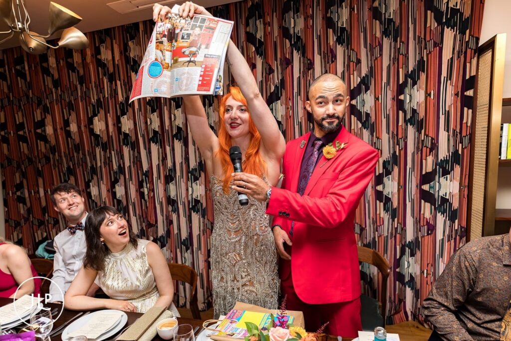 The newlyweds presenting a magazine clipping during a speech at their wedding reception.