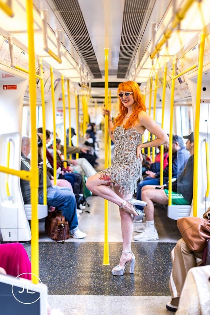 A stylish bride poses against a yellow pole inside a London Tube carriage on her wedding day.