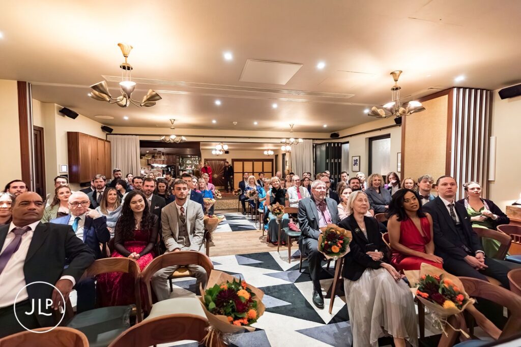 A wide shot of wedding guests seated for a ceremony at The Hoxton Holborn in London.