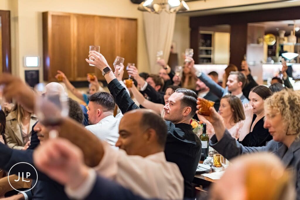 Documentary London wedding photographer shot of guests toasting during a stylish London wedding reception.