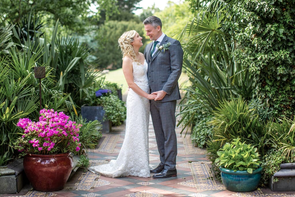 Couples portrait in lush conservatory gardens by a Surrey wedding photographer.