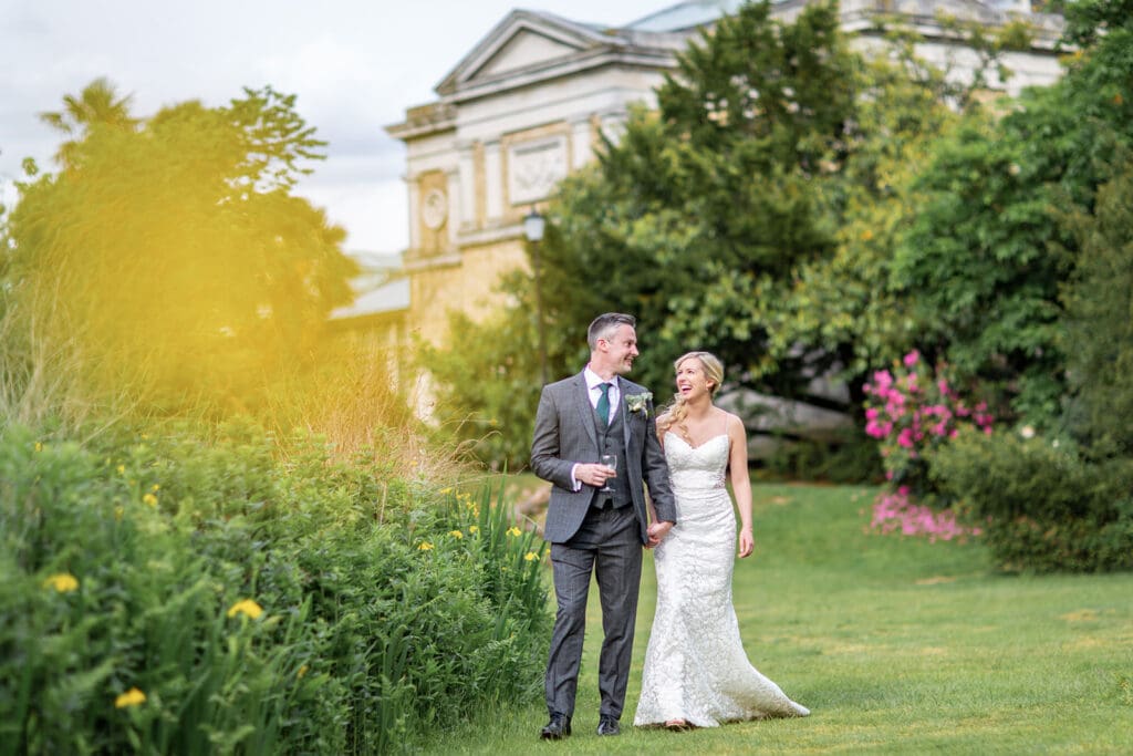 Bride and groom walking and laughing during their Hampton Court House Surrey wedding.